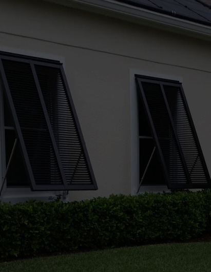Black Bahama hurricane shutters for windows on Florida home, angled exterior storm protection with ventilation