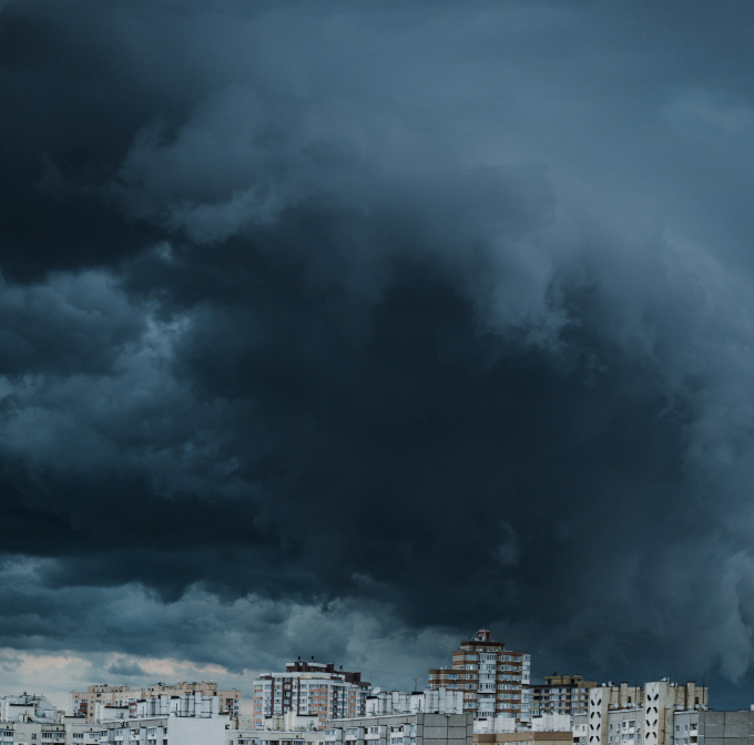 Dark storm clouds over city skyline before hurricane, highlighting need for window storm shutters in Florida