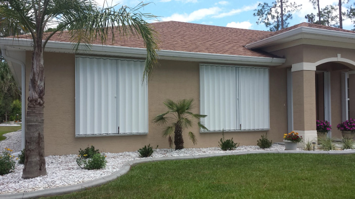 White accordion hurricane shutters for windows on Florida home, exterior storm shutters fully deployed