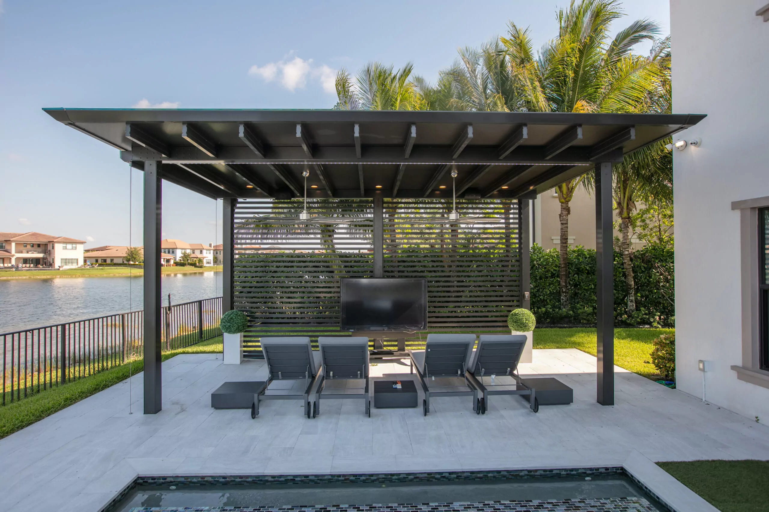 Modern louvered hurricane shutters on Florida patio pergola, exterior storm protection with poolside seating