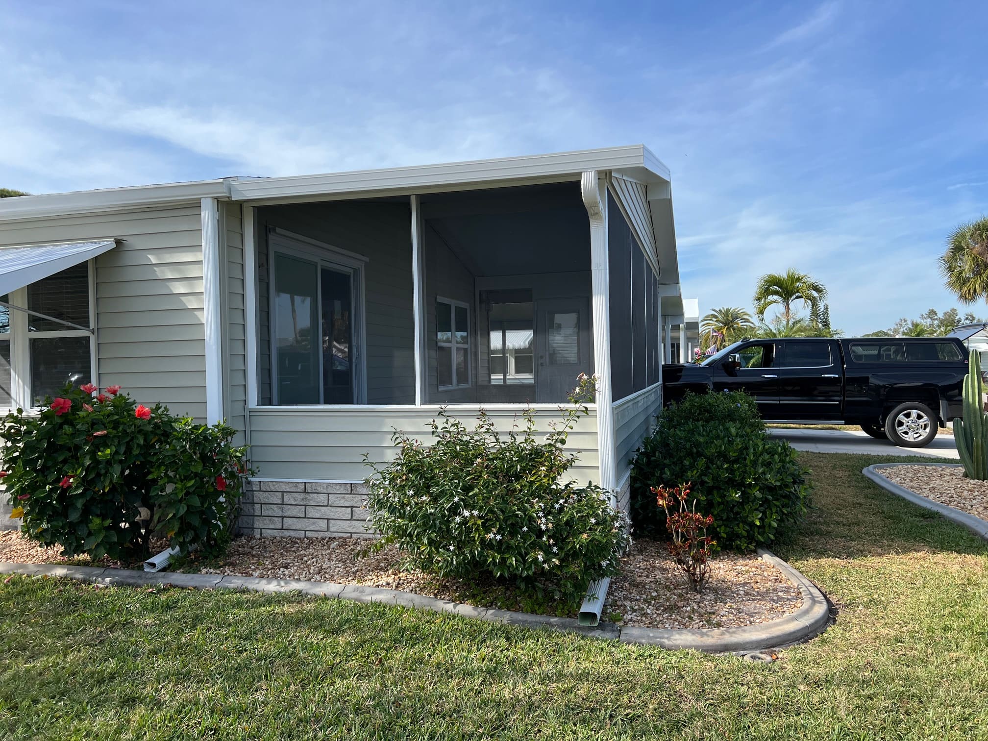 Hurricane shutters for windows on a Florida manufactured home, screened storm protection enclosure