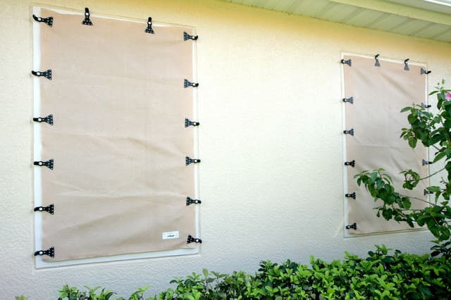 Beige fabric hurricane shutters for windows on a Florida home, exterior storm protection installation